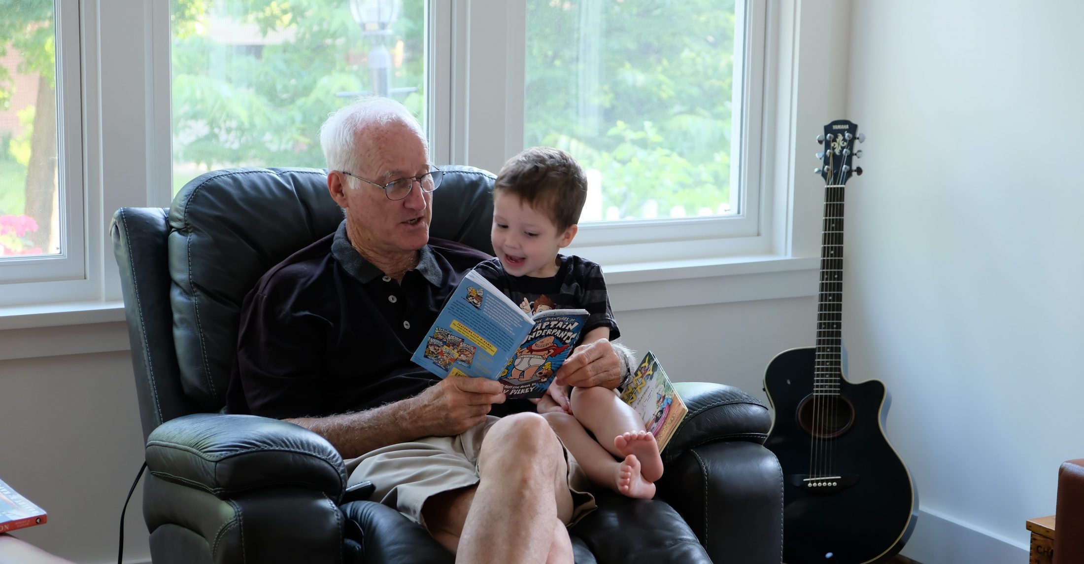 Grandpa Tom Clark reads a book to Tommy Brimley