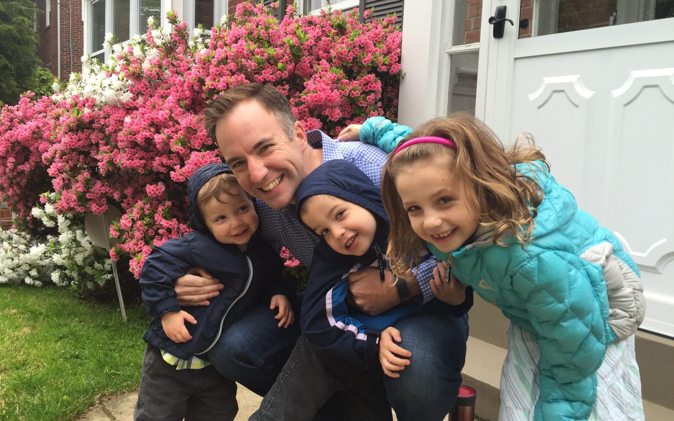 Shawn Brimley and his three children hugging in front of their DC home